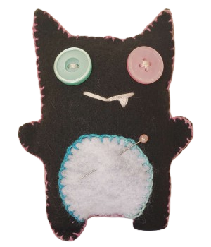 a black felt doll shaped vaguely with demon horns, one pink and one blue button eye, an embroidered smile with a fang, a white tummy with blue stitching, a pin-tipped pin stuck through the tummy, and  pink blanket stitching around the edges of the body.