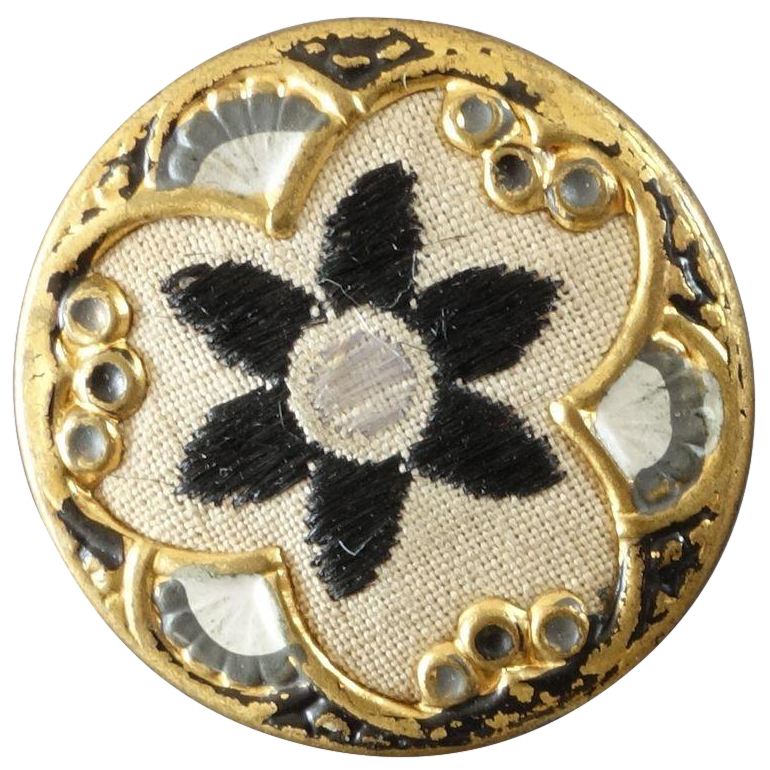 a gold antique button resembling a pansy with 3 petals and cream-and-navy embroidery in the middle